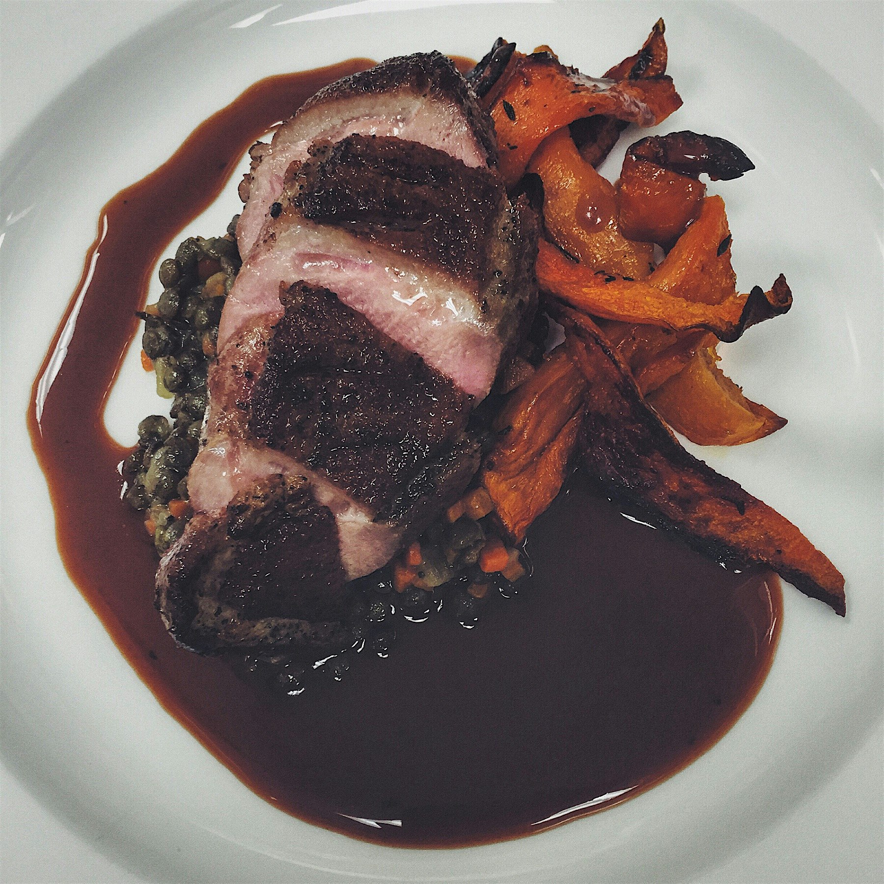 Seared campus raised duck, French lentils, honey cup squash and local plum jus. 
