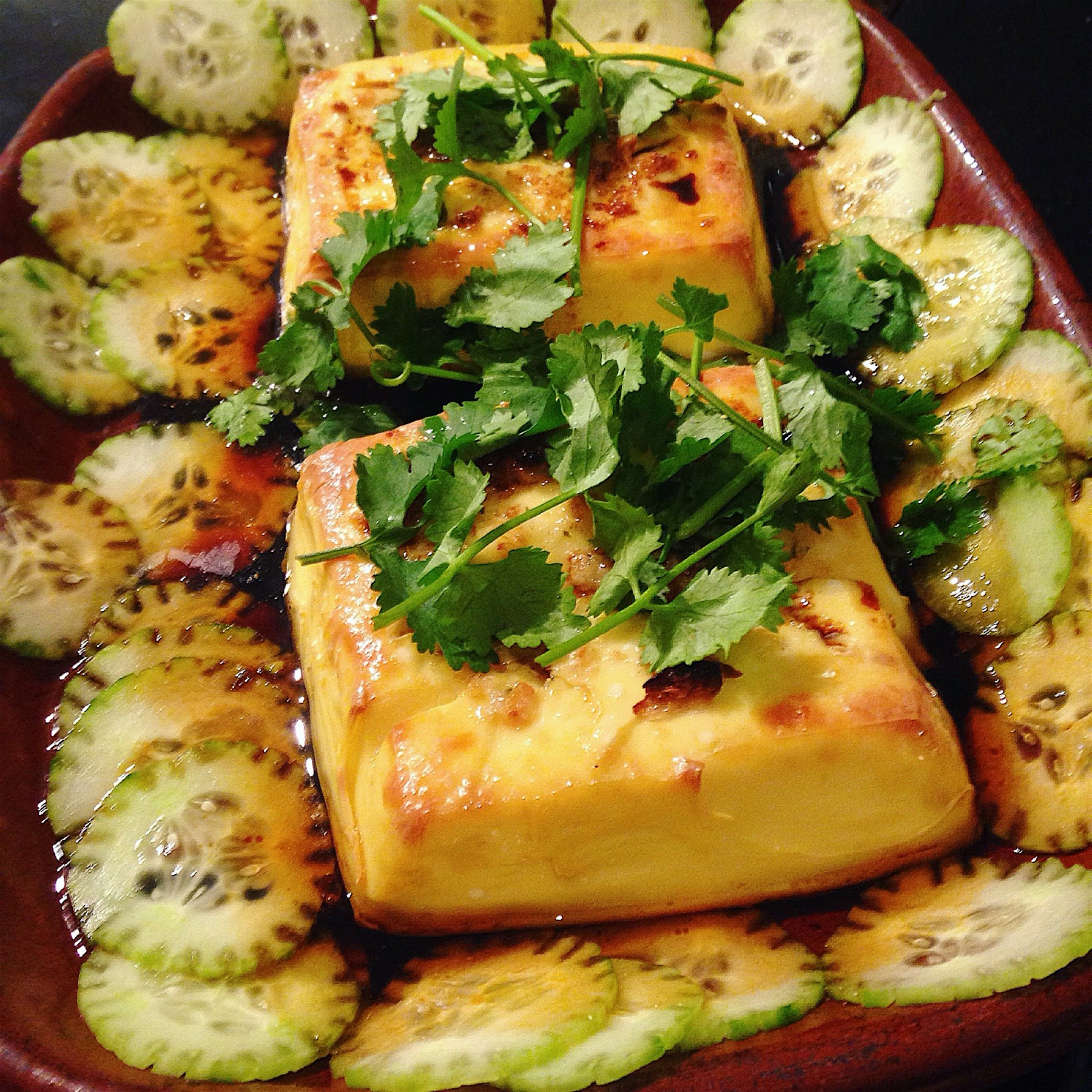Baked egg tofu. Garnished with cilantro and cukes, flavored with garlic, lime leaf, soy and sesam...