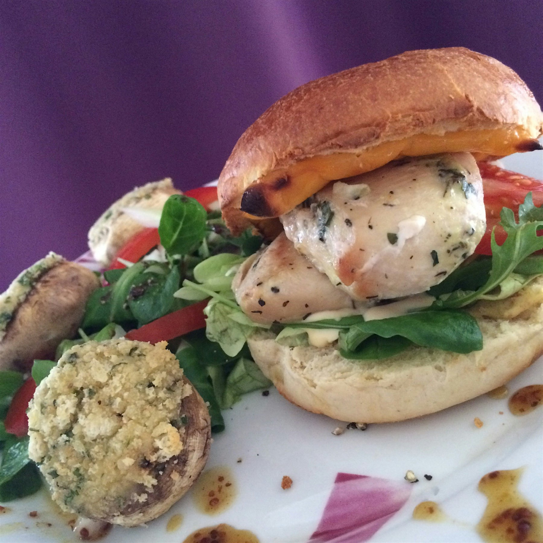 Homemade marinated chicken breast burger with a honey mustard sauce and some stuffed mushrooms 