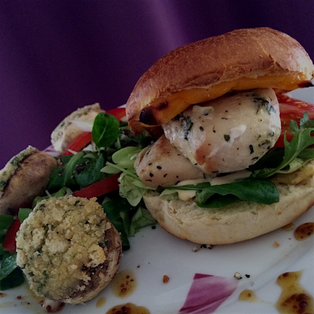 Homemade marinated chicken breast burger with a honey mustard sauce and some stuffed mushrooms 