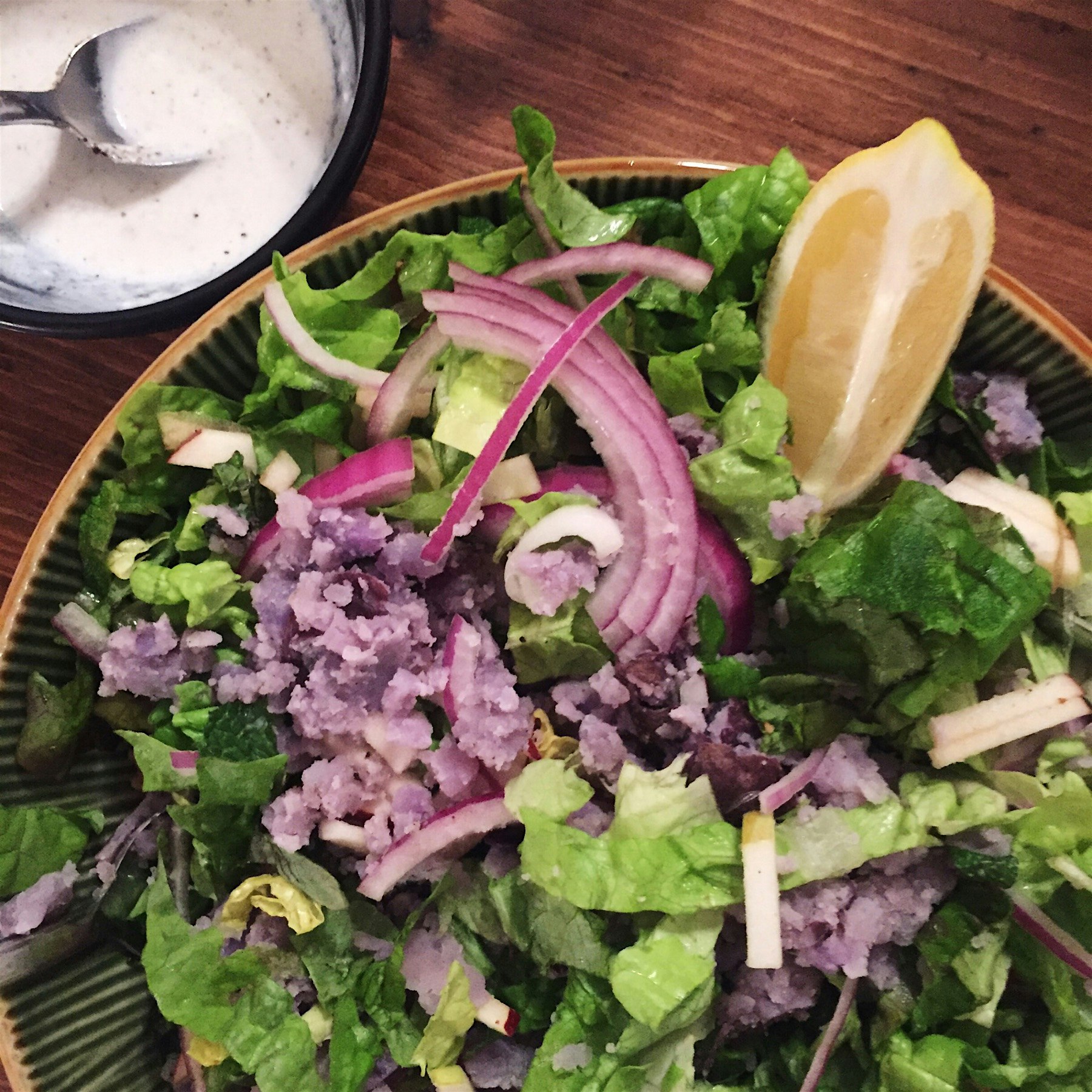 Olive oil smashed purple potatoes, red onion, apples and pecans over red leaf lettuce with a lemo...