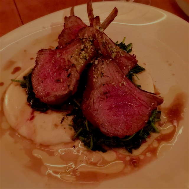 Lamb served with olive oil whipped potatoes, grilled pea leaves, rosemary gremolata, and natural ...