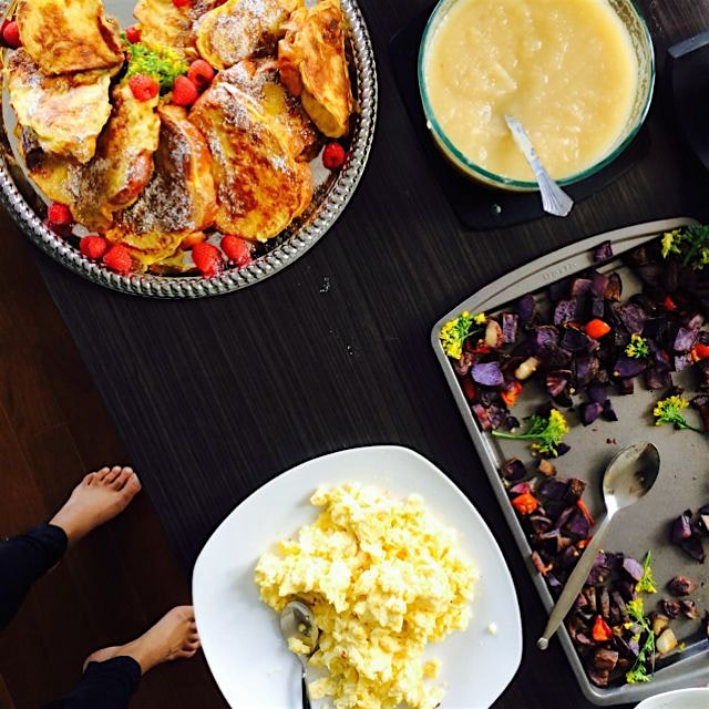 An overhead shot of brunch. Creamy scrambled eggs, challah French toast, purple potatoes, & maple...