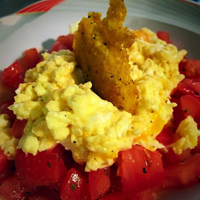 Breakfast for the family reunion. Scrambled eggs on a tomato salad topped with a polenta fritter.