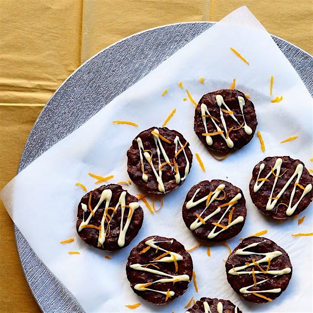 Gluten-free chocolate brownie cups with orange zests and chopped almonds inside.