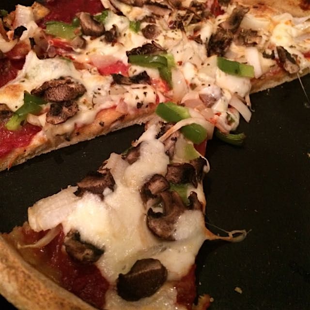 Homemade deep dish veggi pizza baked in a cast iron pan with fresh Mozzarella 