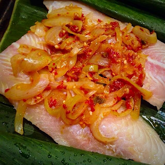 Flounder topped with onions and Sambal, ready to be wrapped up in banana leaves and roasted. #the...