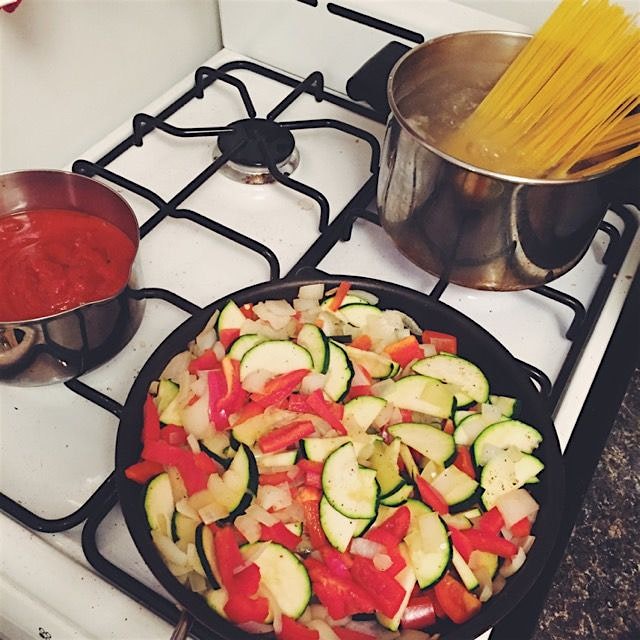 On tonight's stove top: zucchini, onions and peppers; marinara; gluten-free spaghetti 