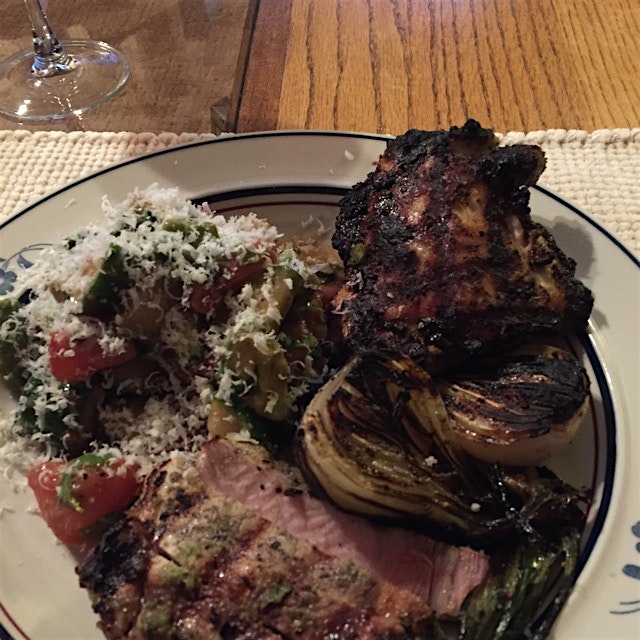 Dry aged pork chops with sofrito, charred spring onions, tomato avocado salad with fresh basil an...