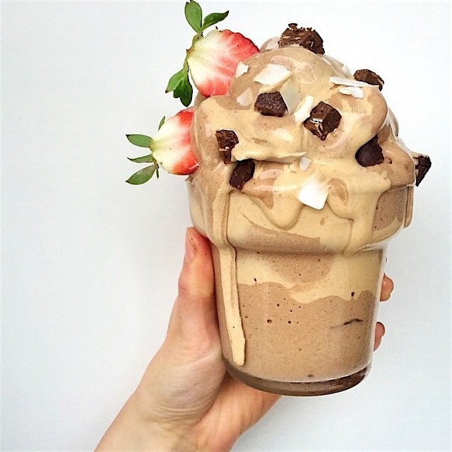 Carob nana cream with peanut butter drizzle, topped with Squarebar chunks, coconut chips and stra...