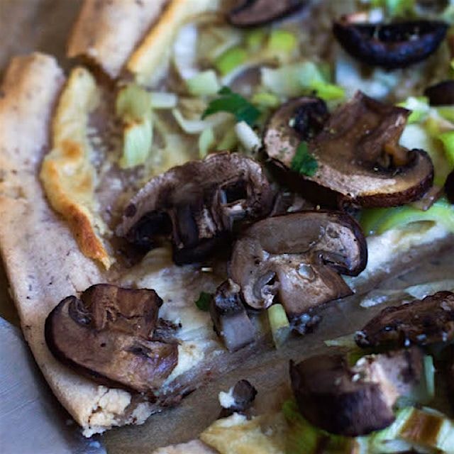 Flatbread pizza made with cassava flour, cashew cheese, leeks and mushrooms. Gluten-free, vegan a...