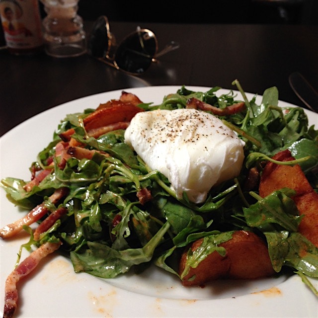 Perfectly poached goodness over dressed arugula with house-cured bacon lardons. 