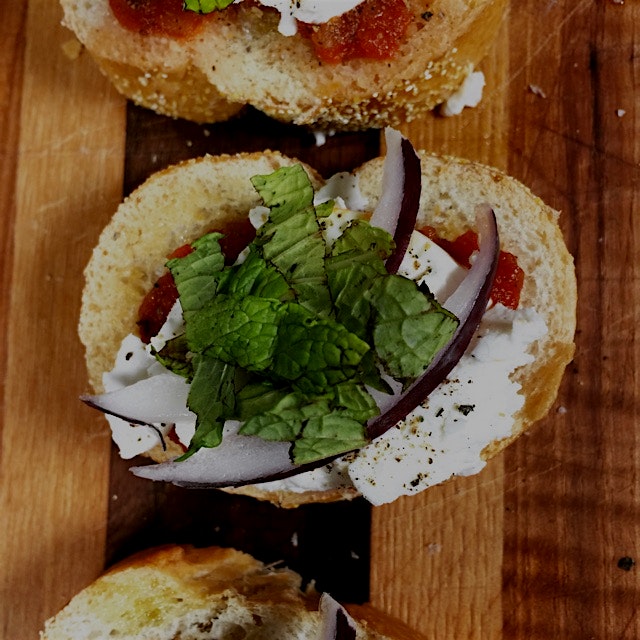 Goat cheese bruschetta with red onion, garlic, diced tomatoes, and fresh mint.
