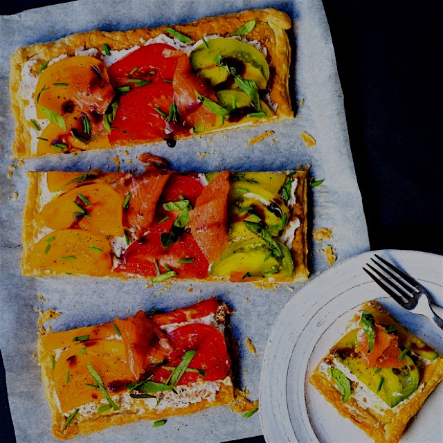 An Heirloom and smoked salmon tart on a spread of ricotta cheese mixed with lemon zest, drizzled ...