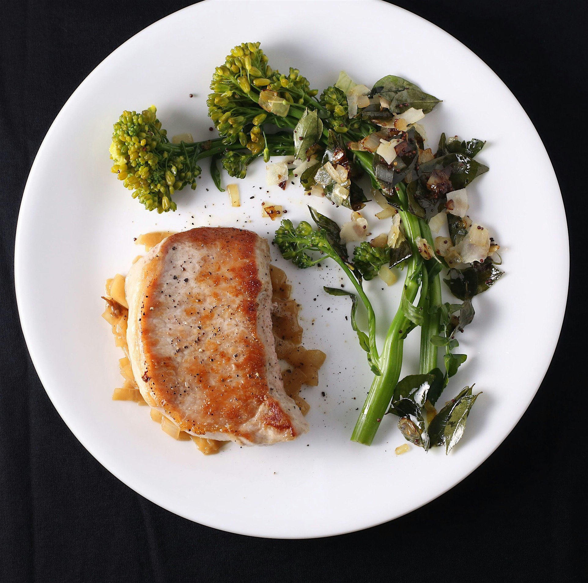 Pork chops and broccoli raab with coconut flakes and shallots.