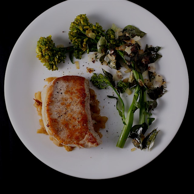 Pork chops and broccoli raab with coconut flakes and shallots.