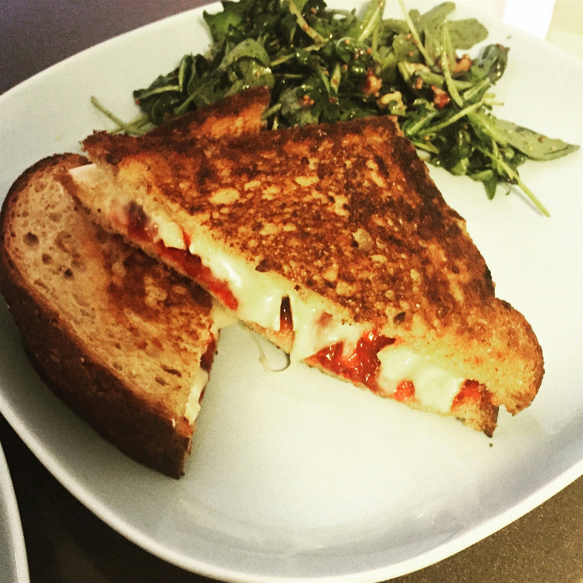 Grilled brie and homemade strawberry jam sandwich with arugula and toasted walnut salad