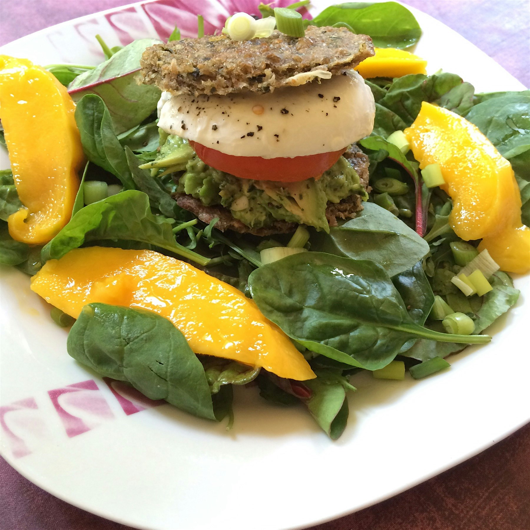 Homemade vegetarian burger : guacamole, tomatoes, mozzarella cheese between two cereals, spinach ...