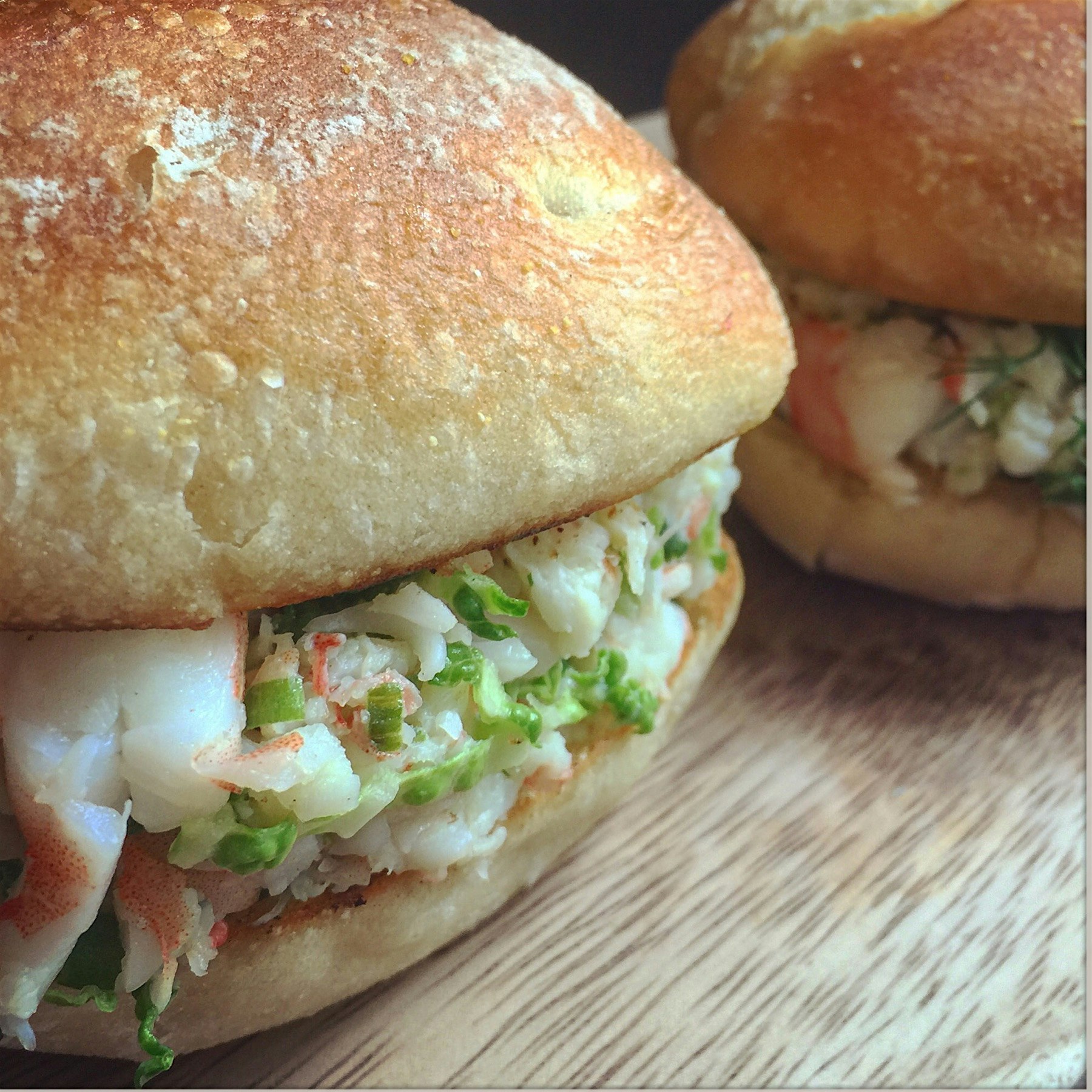 Shrimp rolls with chives fennel cabbage and butter on a warm sourdough bread roll