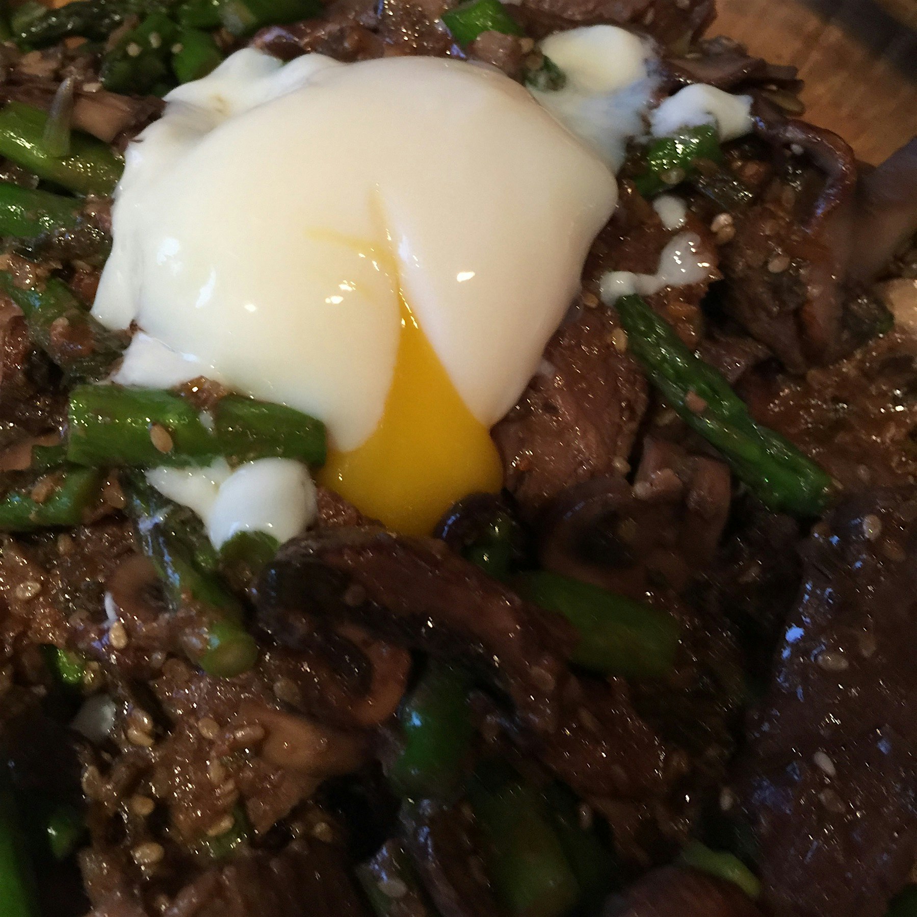 Sous Vide Korean beef steak with asparagus and mushrooms served over rice topped with a poached egg 