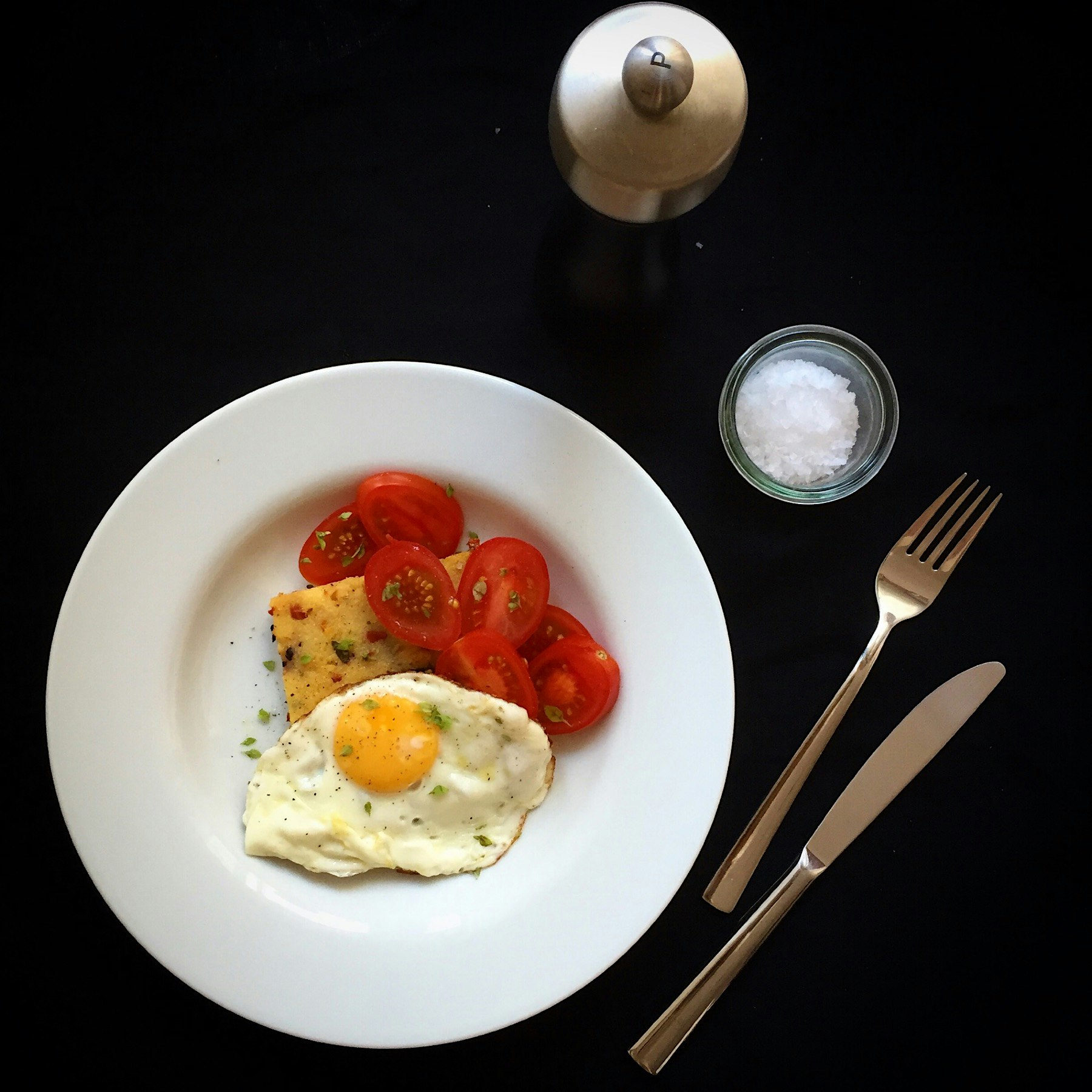 Another simple breakfast with fried egg: pan-fried polenta with mini plum tomatoes, topped with f...