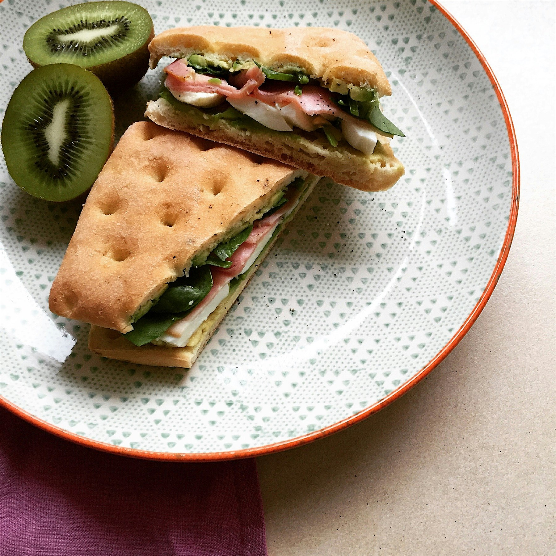 Mashed avocado, ham, boiled egg and baby spinach in focaccia 