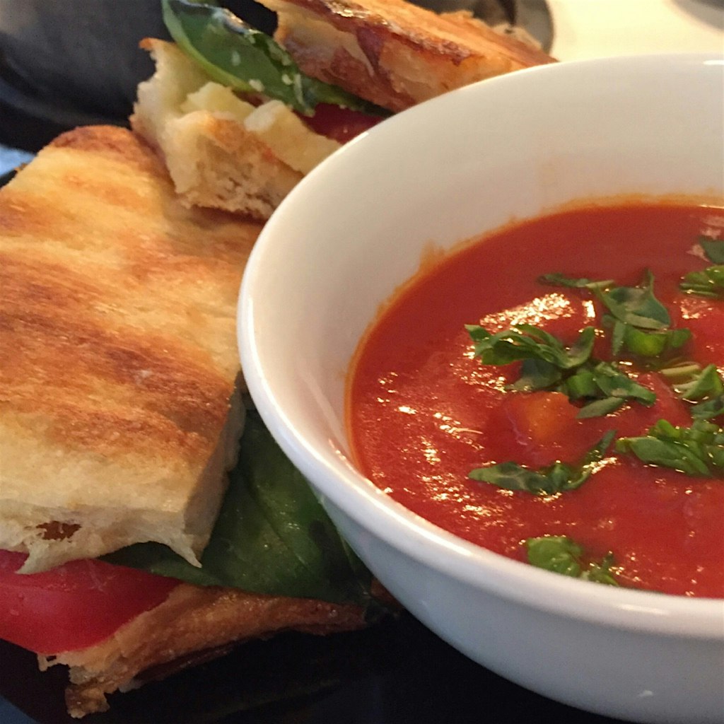 Comfort food lunch griiled cheese with aged cheddar, tomatoes, basil on focaccia with creamy toma...