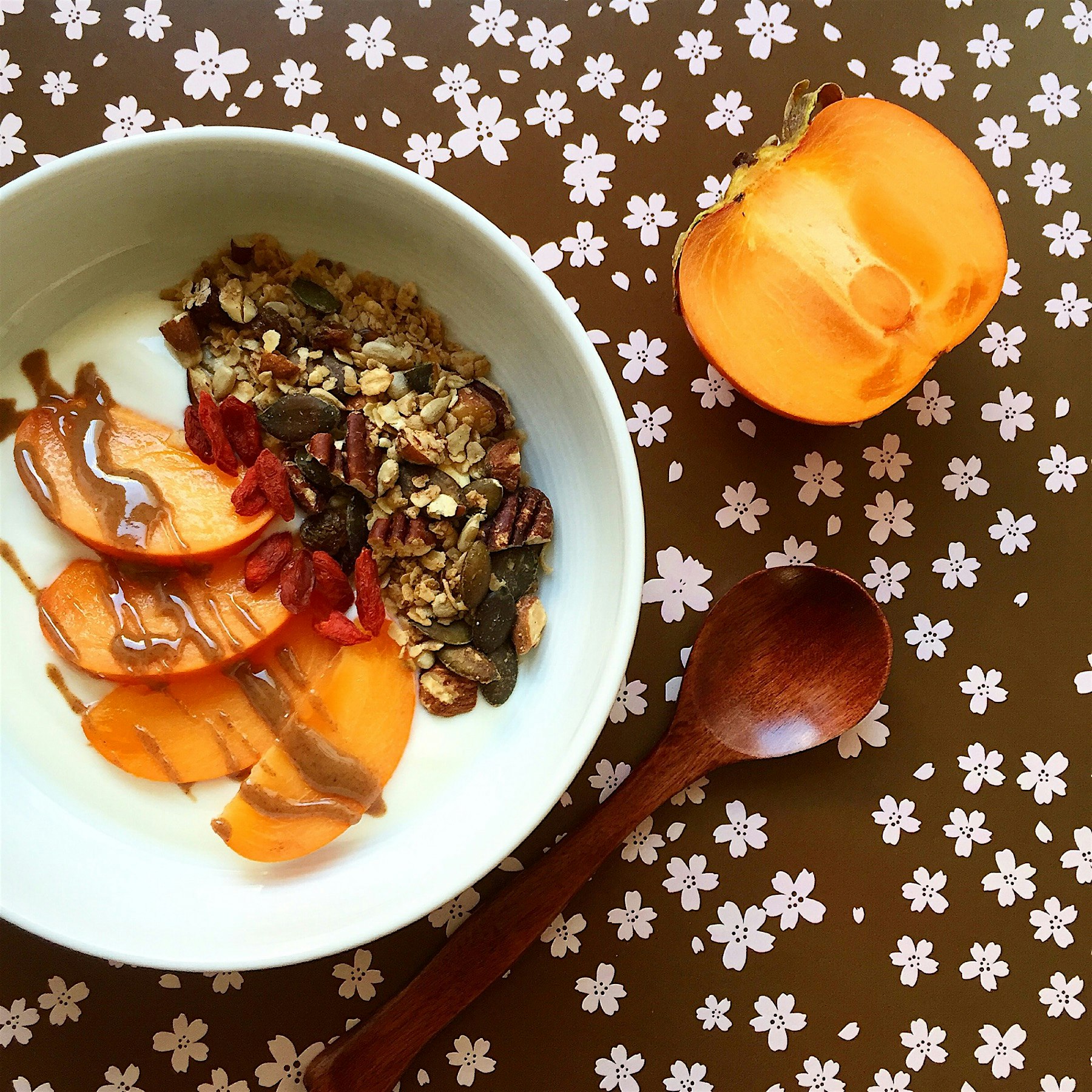 Love this breakfast of yogurt with homemade cinnamon granola, persimmon, almond butter and goji b...