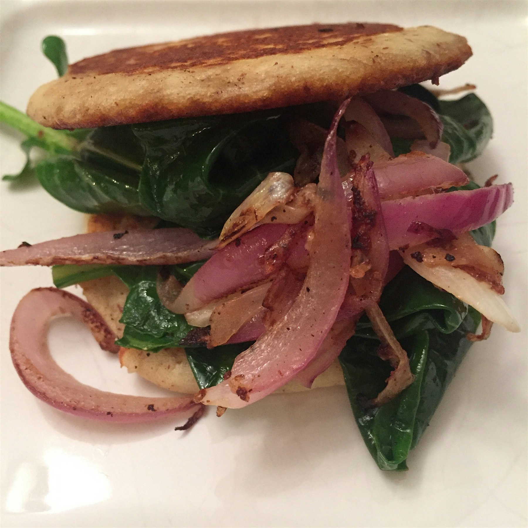 Sautéed collard sandwich using gluten free savory pancakes instead of cornmeal. Deep South comfor...